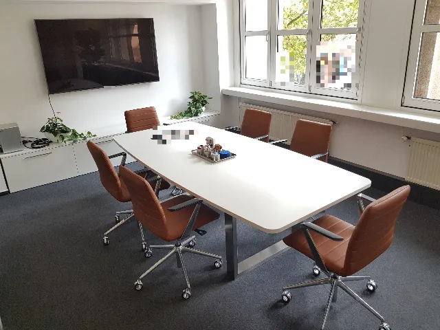 Besprechungsraum mit Tisch, Lederstühlen und Bildschirm