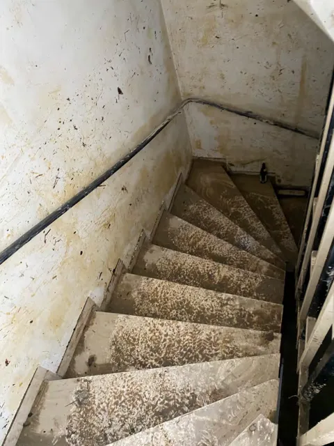 Kellertreppe und Wände voller Schlamm nach einer Überschwemmung durch Starkregen und Rückstau