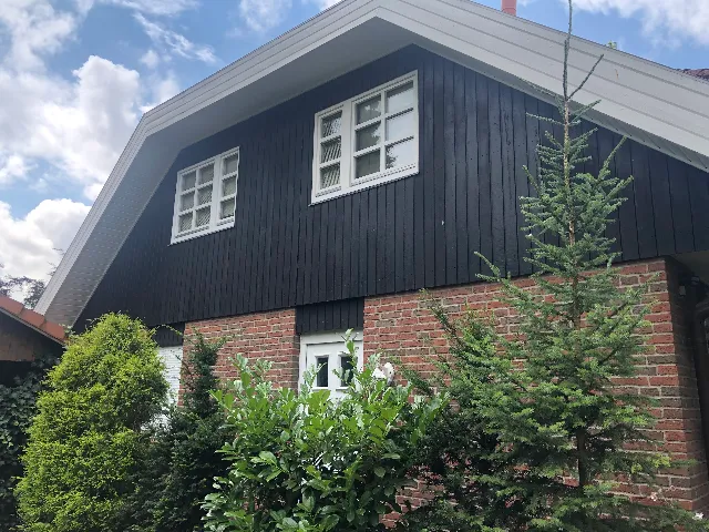 Einfamilienhaus mit Klinker im Erdgeschoss und dunkler Holzverschalung am Giebel